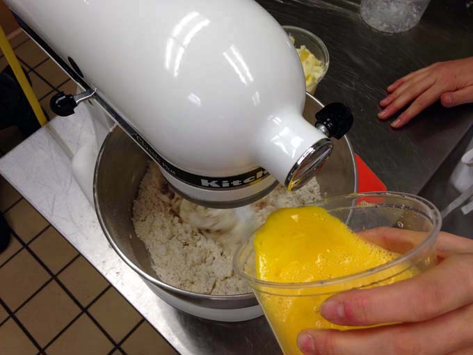 Adding eggs to brioche dough at Braise Culinary School