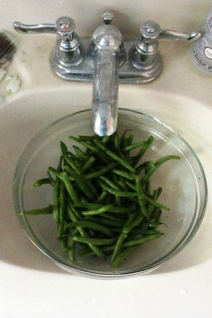 Cleaning fresh green beans in a bathroom sink